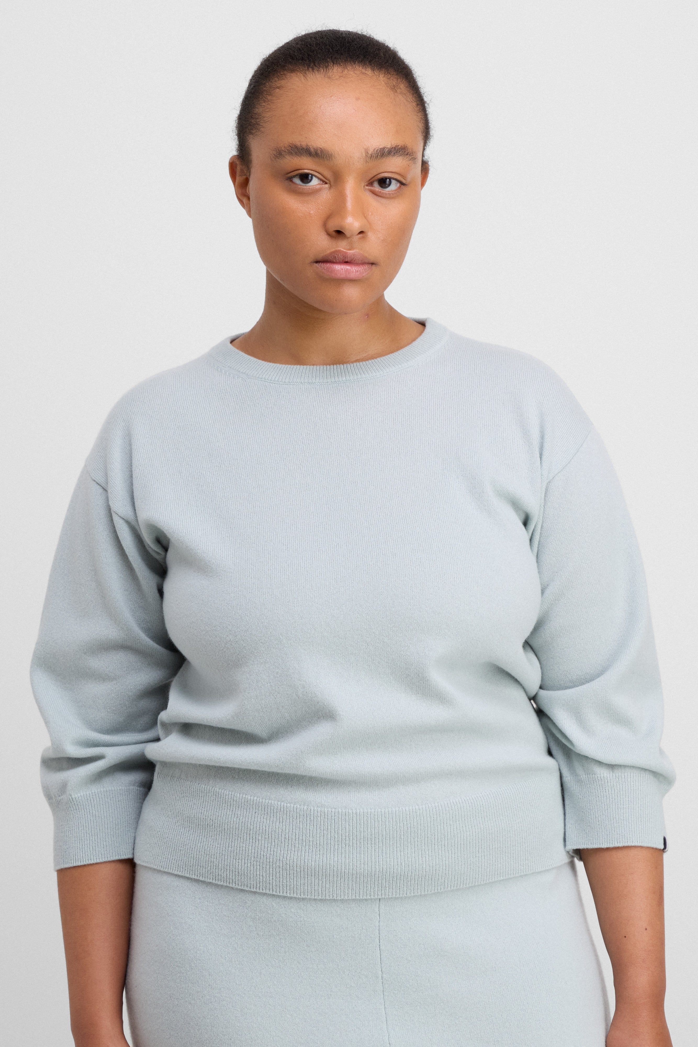 woman wearing a pale blue 3/4-sleeve cashmere crewneck sweater.
