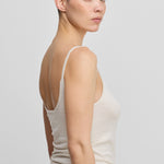 woman wearing a white cotton cashmere strap top with a low back, shown from the side.