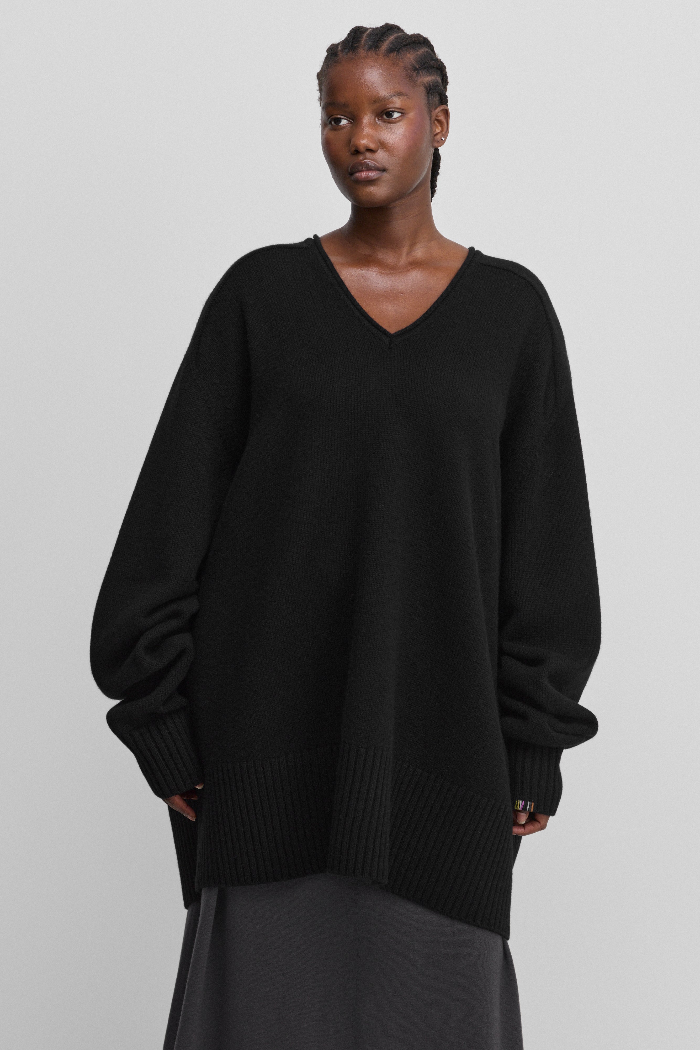 woman wearing a black oversized cashmere v-neck sweater with ribbed hem and cuffs and extra long sleeves.