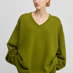 woman wearing a green oversized cashmere v-neck sweater with ribbed hem and cuffs.