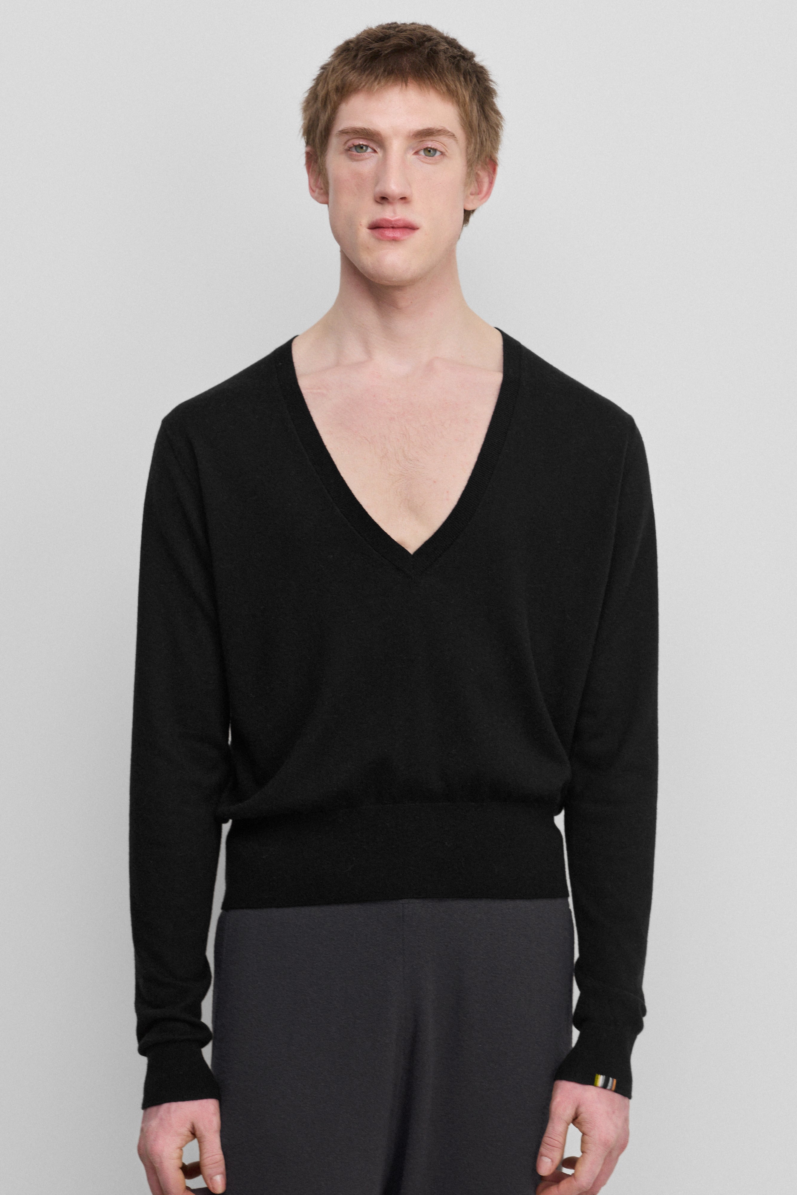 man wearing a black wool cashmere v-neck sweater with ribbed hem and cuffs.