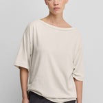 woman wearing an oversized white cotton cashmere t-shirt with a boat neck and elbow-length sleeves.