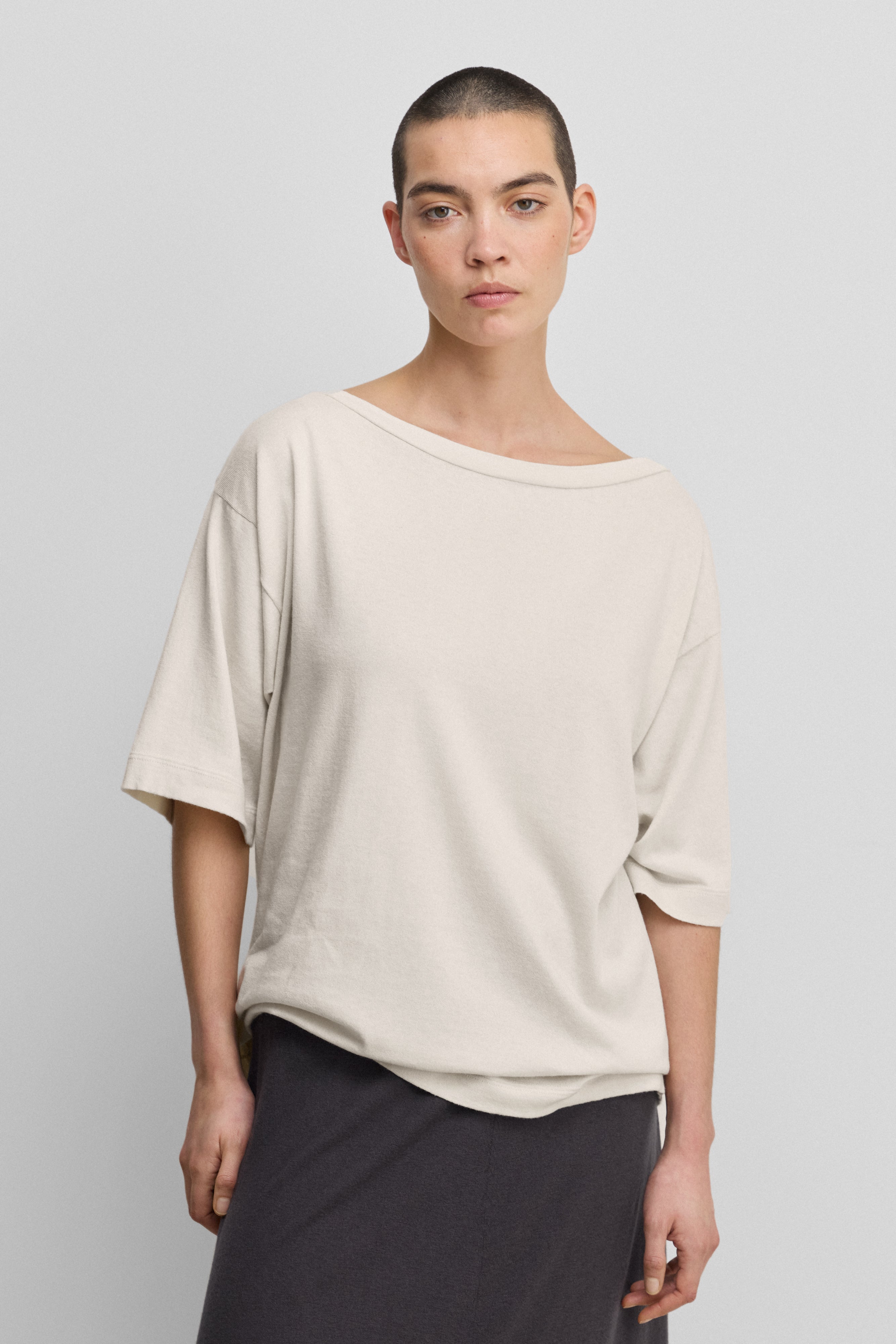 woman wearing an oversized white cotton cashmere t-shirt with a boat neck and elbow-length sleeves.