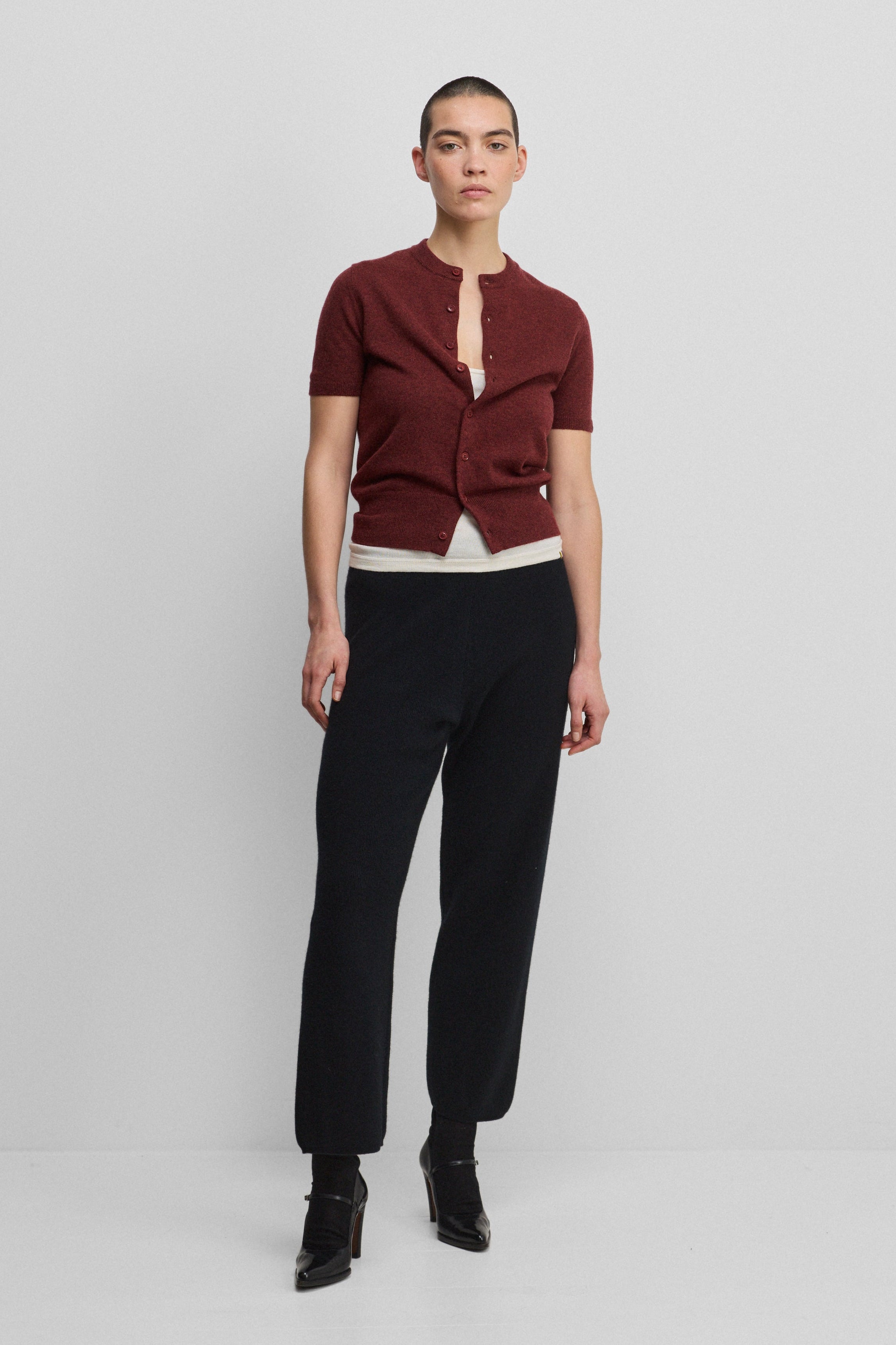 woman wearing black rib-knit cashmere pants with straight legs, styled with a burgundy cardigan.