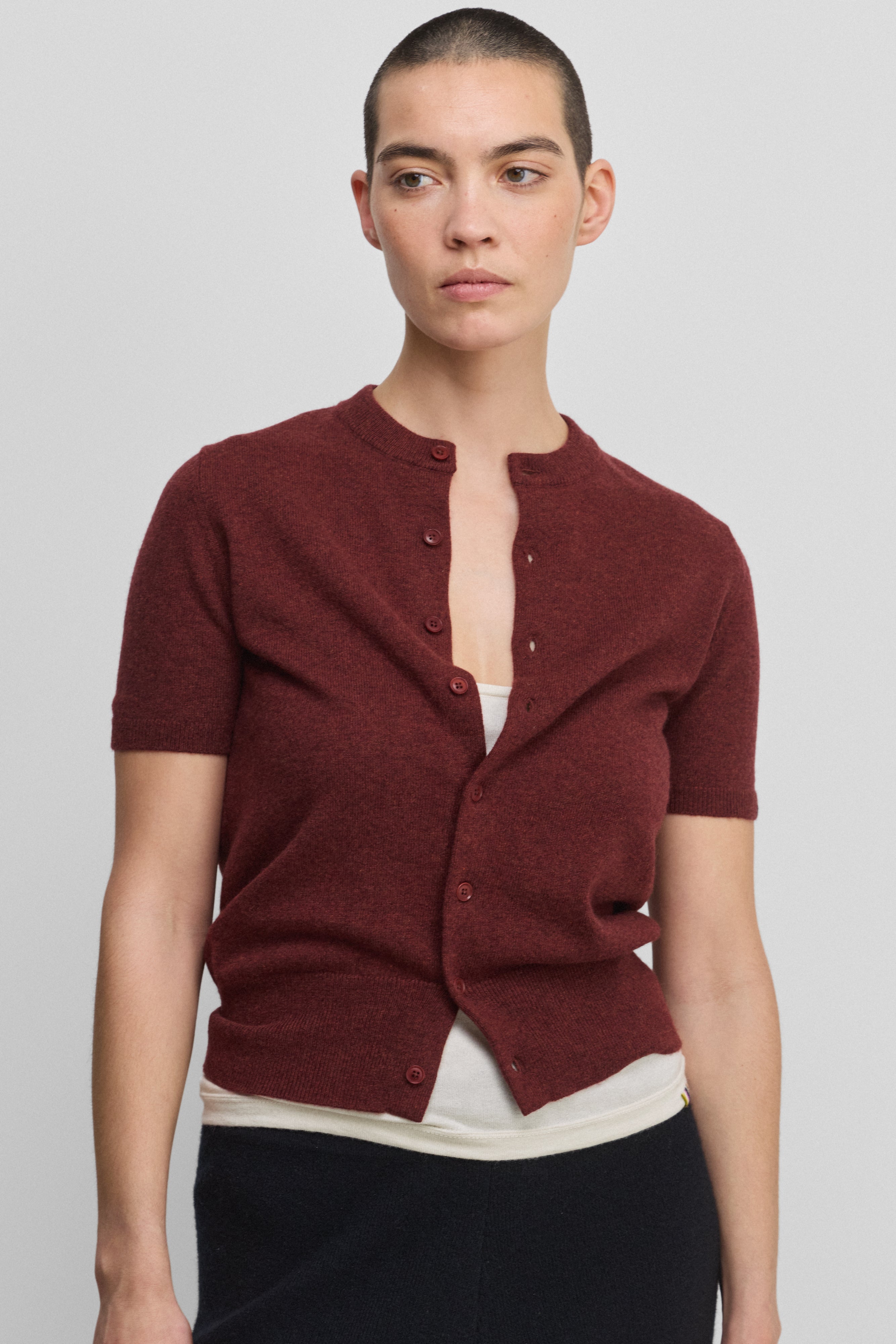 woman wearing a burgundy short-sleeved cashmere button-up cardigan with rib-knitted hem and cuffs.