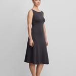 woman wearing a dark grey sleeveless wool cashmere a-line dress in midi length with a boat neckline.