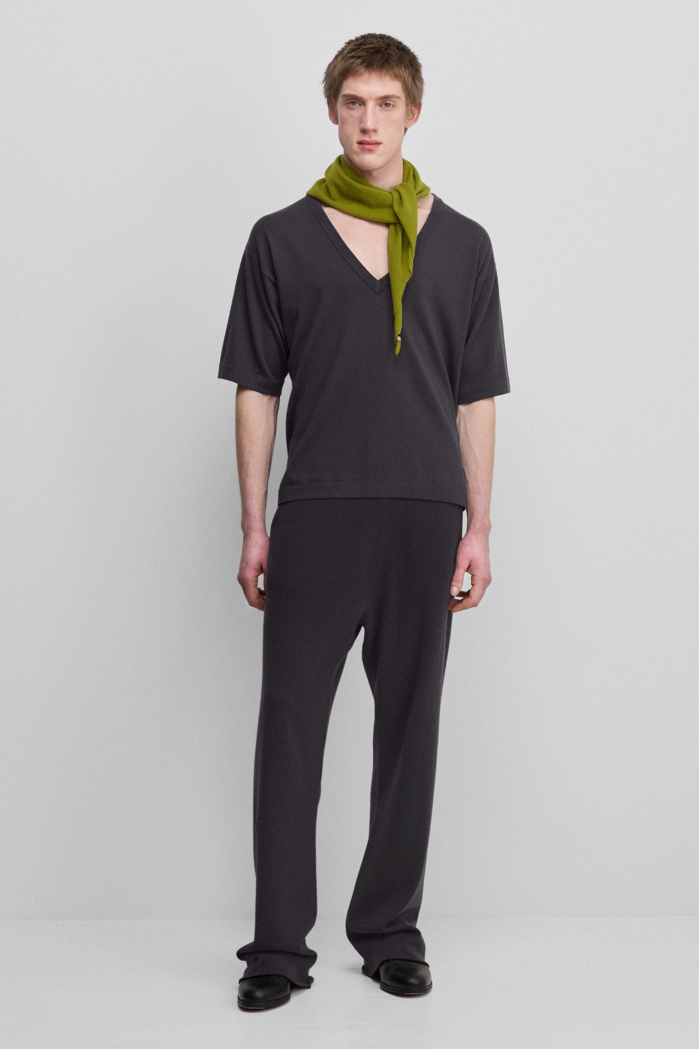 man wearing dark grey loose-fit cashmere pants with a drawstring waistband and side pockets.
