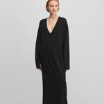 woman wearing a black long-sleeved maxi dress with a deep v-neck in cotton cashmere.