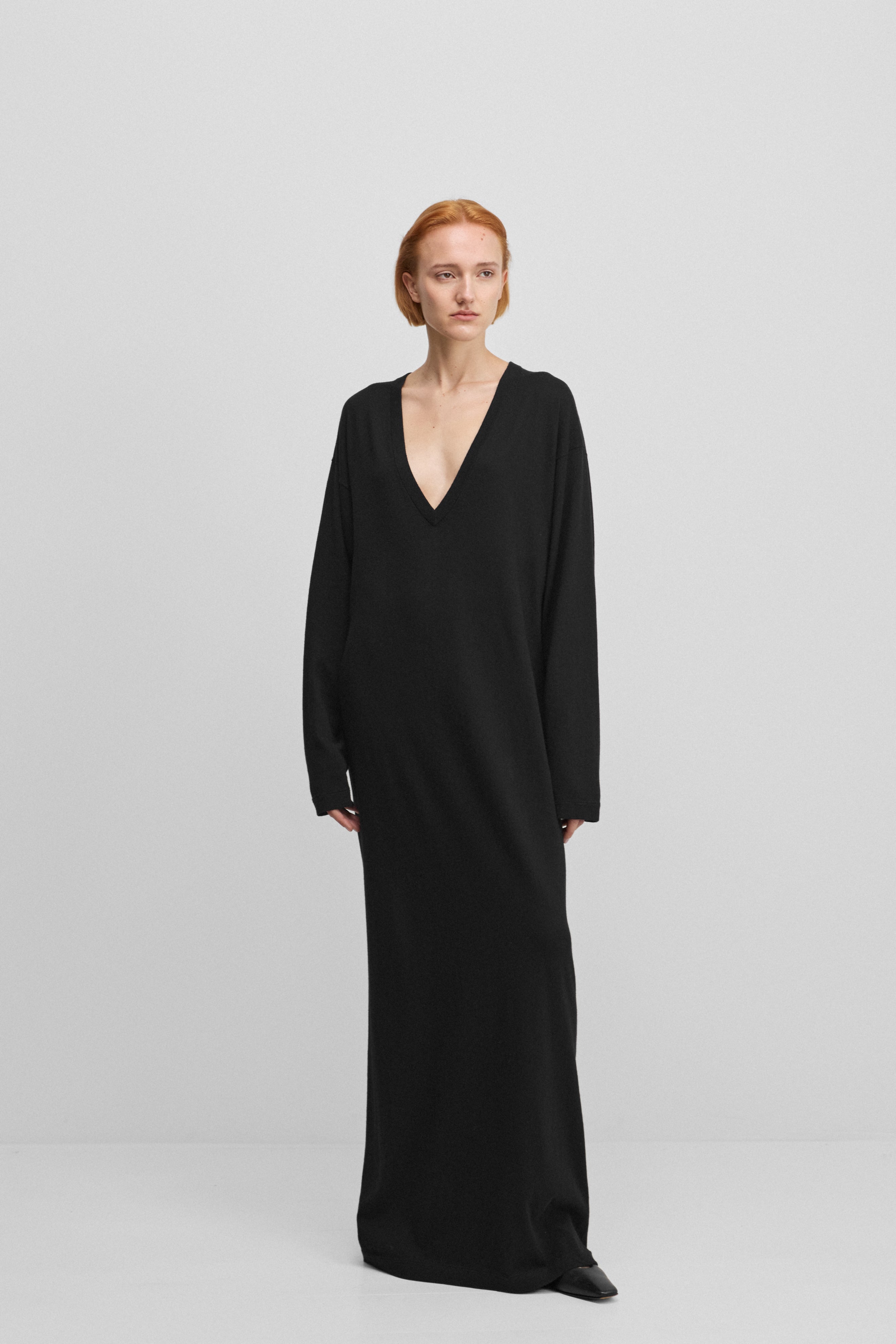woman wearing a black long-sleeved maxi dress with a deep v-neck in cotton cashmere.