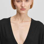 detail of a deep v-neckline of a black long-sleeved t-shirt dress in cotton cashmere.