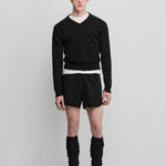 man wearing black rib-knit cashmere leg warmers, styled with black shorts.