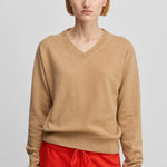 woman wearing a camel beige classic-fit cashmere v-neck sweater with ribbed trims.