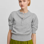 woman wearing a grey half-button cashmere sweater with elbow-length sleeves and ribbed cuffs and hem.