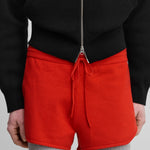 model wearing bright red cotton-cashmere mini-rib shorts with a drawstring and curved hem.