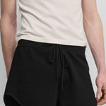 model wearing black cotton-cashmere mini-rib shorts with a drawstring and curved hem.