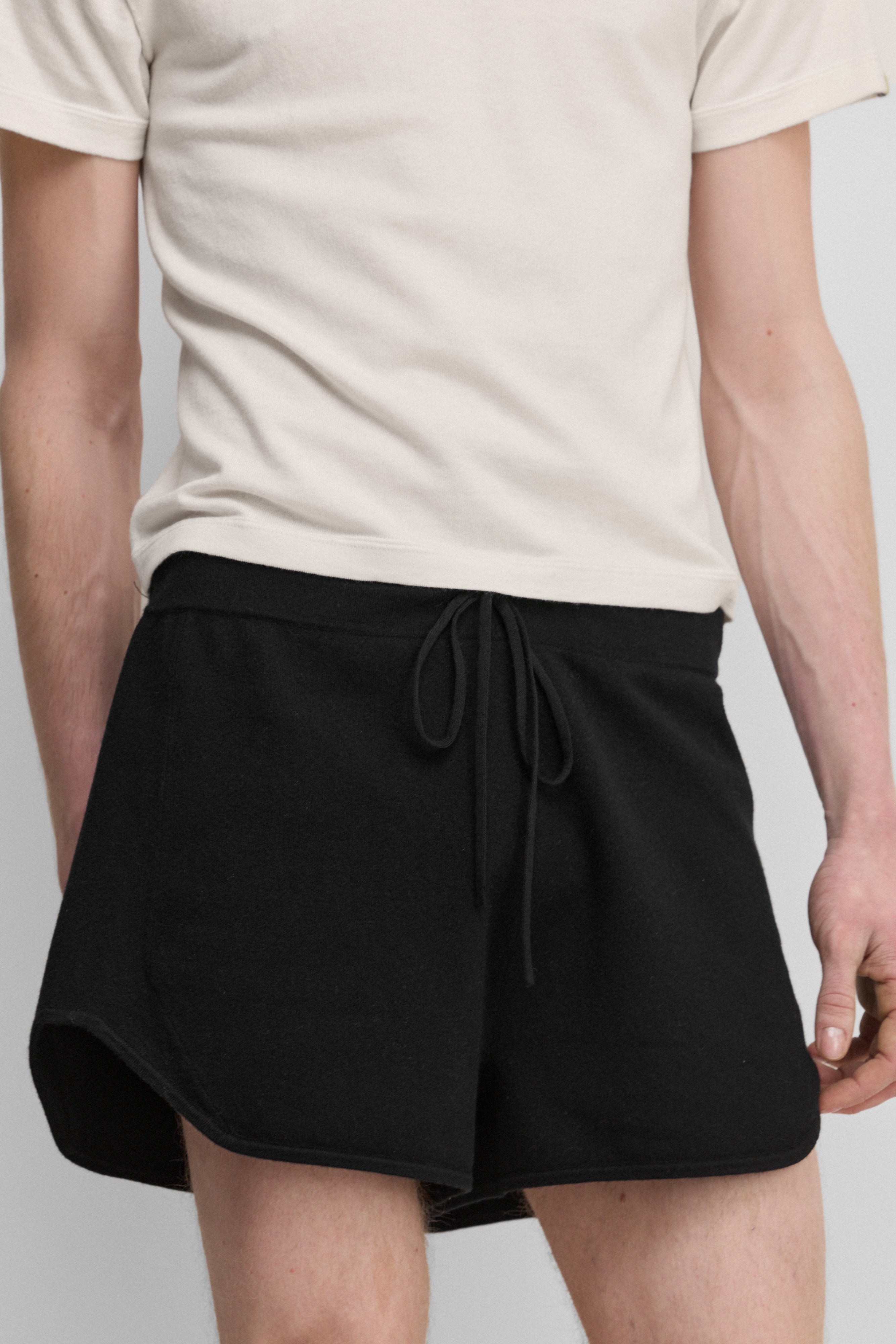 model wearing black cotton-cashmere mini-rib shorts with a drawstring and curved hem.