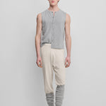 man wearing a light grey sleeveless cotton-cashmere button-up vest with a crewneck, styled with cream pants.