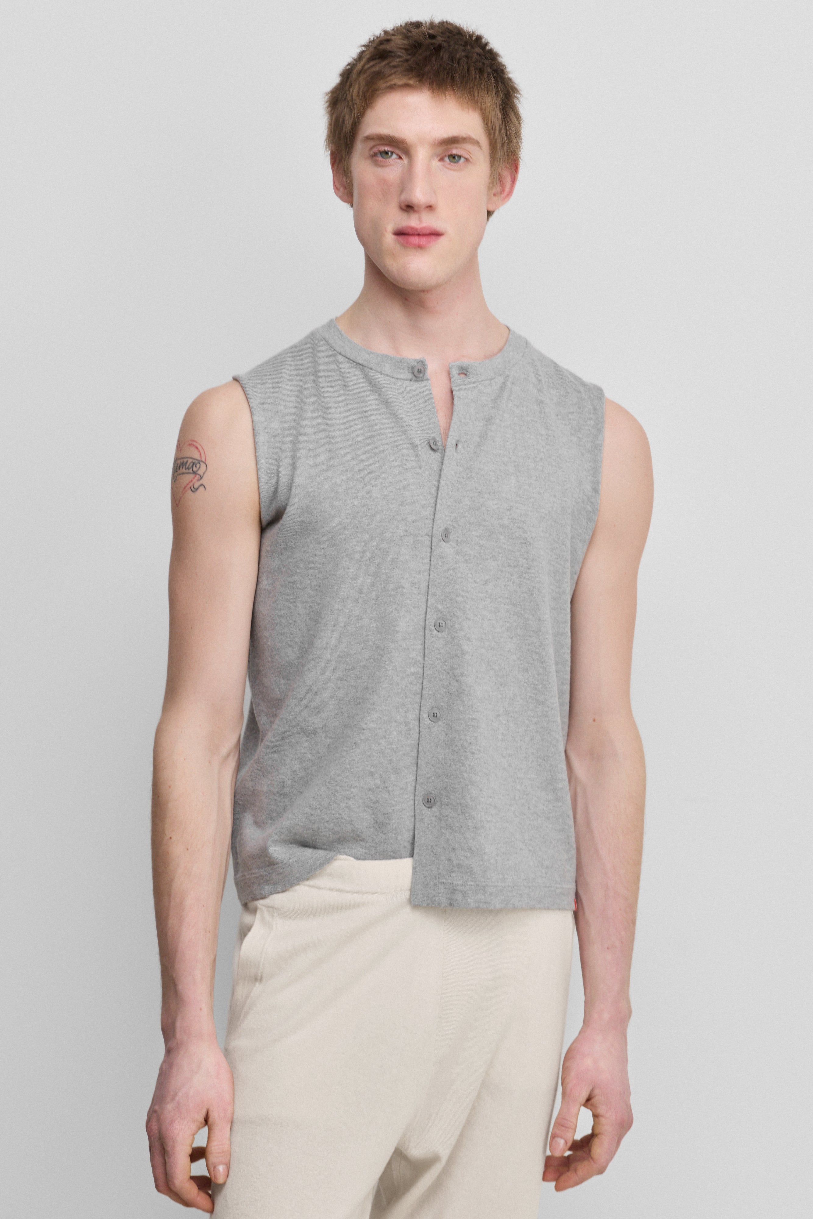 man wearing a light grey sleeveless cotton-cashmere vest with corozo buttons and a crewneck.