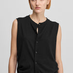 woman wearing a black sleeveless cotton-cashmere vest with corozo buttons and a crewneck.