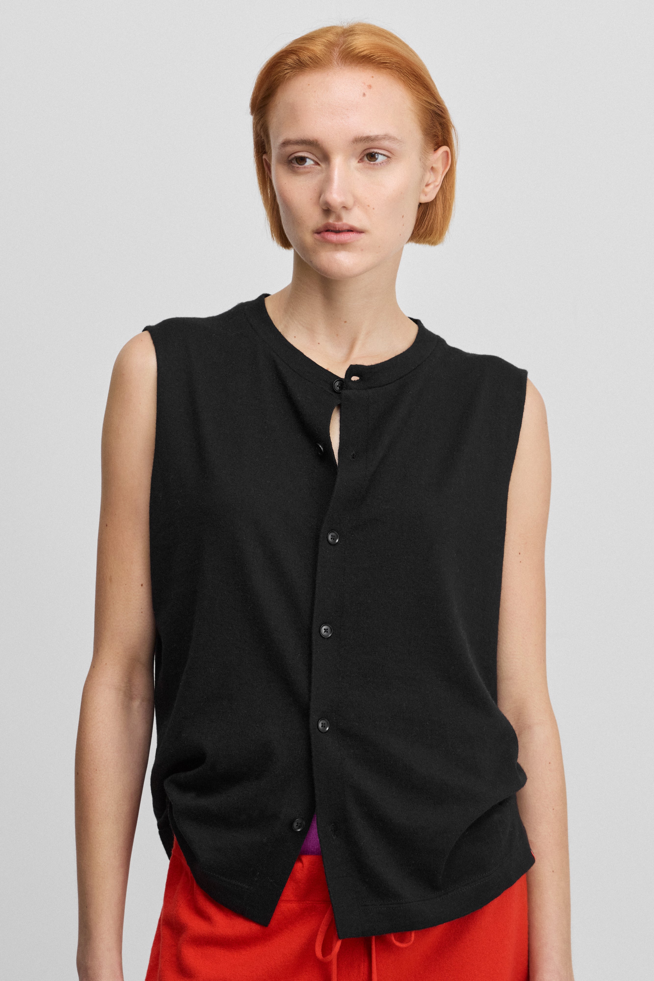 woman wearing a black sleeveless cotton-cashmere vest with corozo buttons and a crewneck.