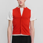 man wearing a bright red sleeveless cotton-cashmere vest with corozo buttons and a crewneck.