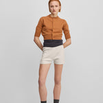 woman wearing white cotton cashmere rib-knit shorts, styled with an orange cardigan.