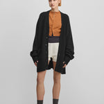 woman wearing a black oversized chunky cashmere button-up cardigan with pockets.