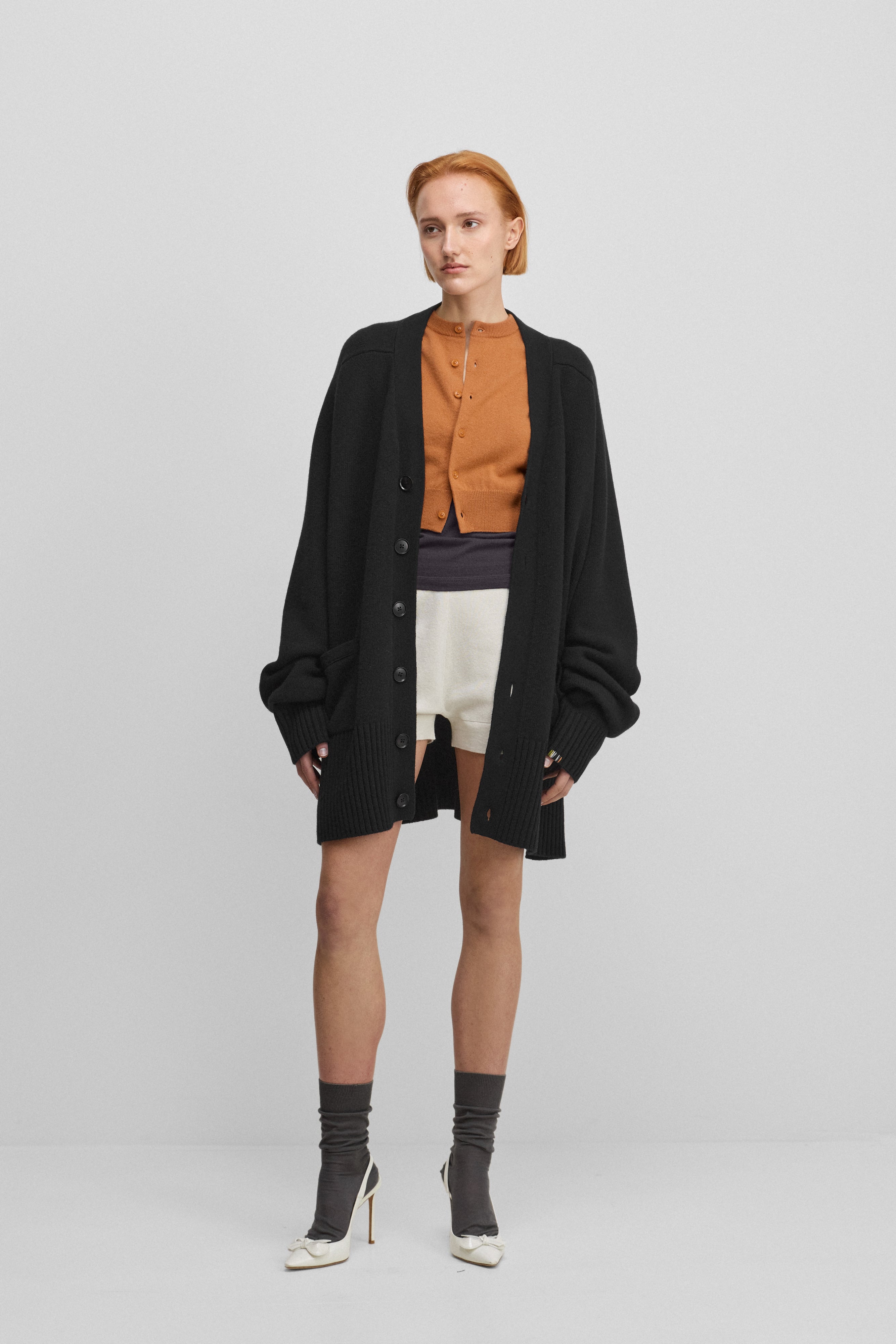 woman wearing a black oversized chunky cashmere button-up cardigan with pockets.