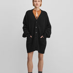 woman wearing a black oversized chunky cashmere v-neck cardigan with  six corozo buttons and pockets.