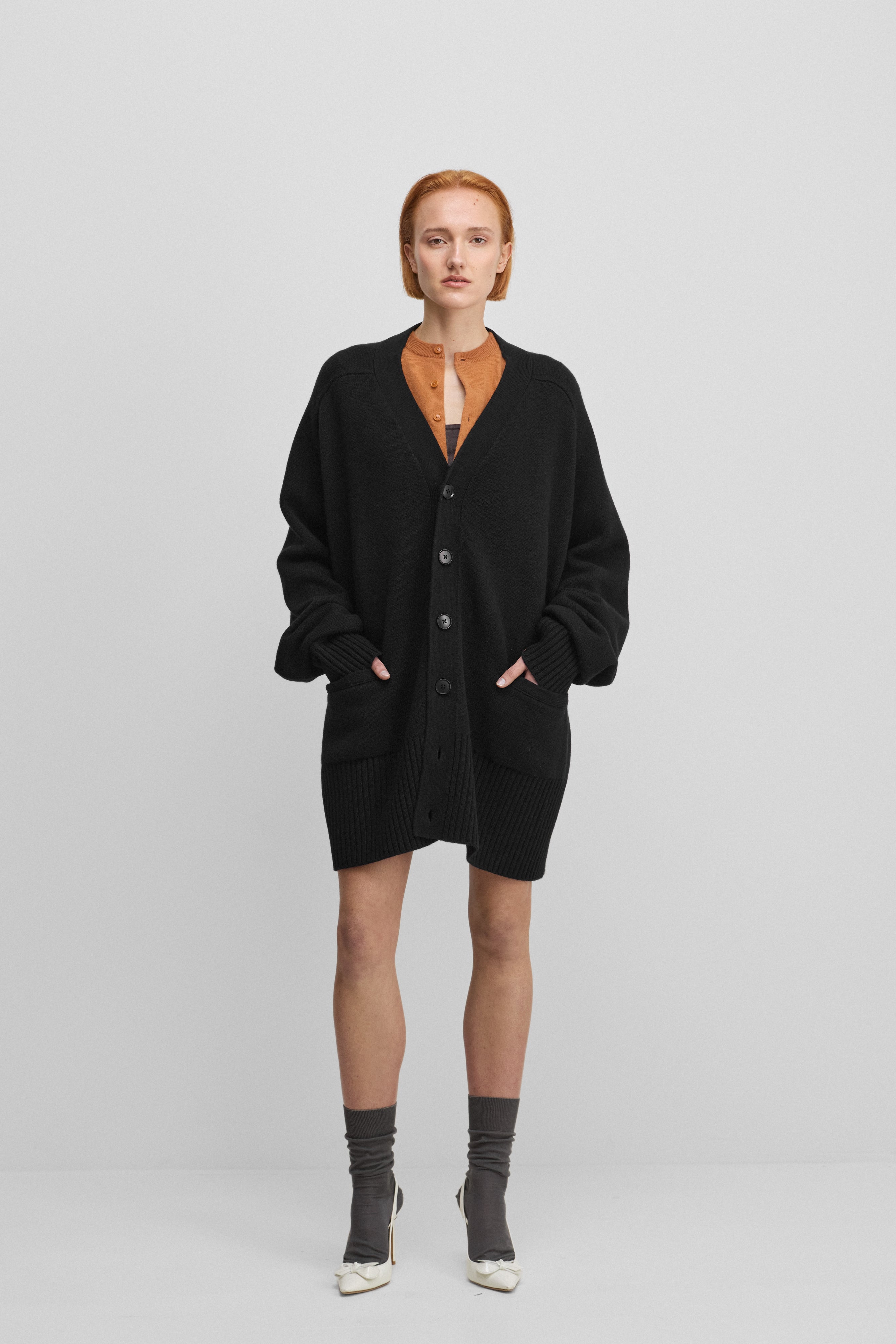 woman wearing a black oversized chunky cashmere v-neck cardigan with  six corozo buttons and pockets.