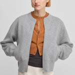 woman wearing a grey cashmere crew-neck cardigan with a metallic two-way zipper and side pockets.