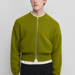 man wearing a green cashmere crew-neck cardigan with a metallic two-way zipper and two side pockets.