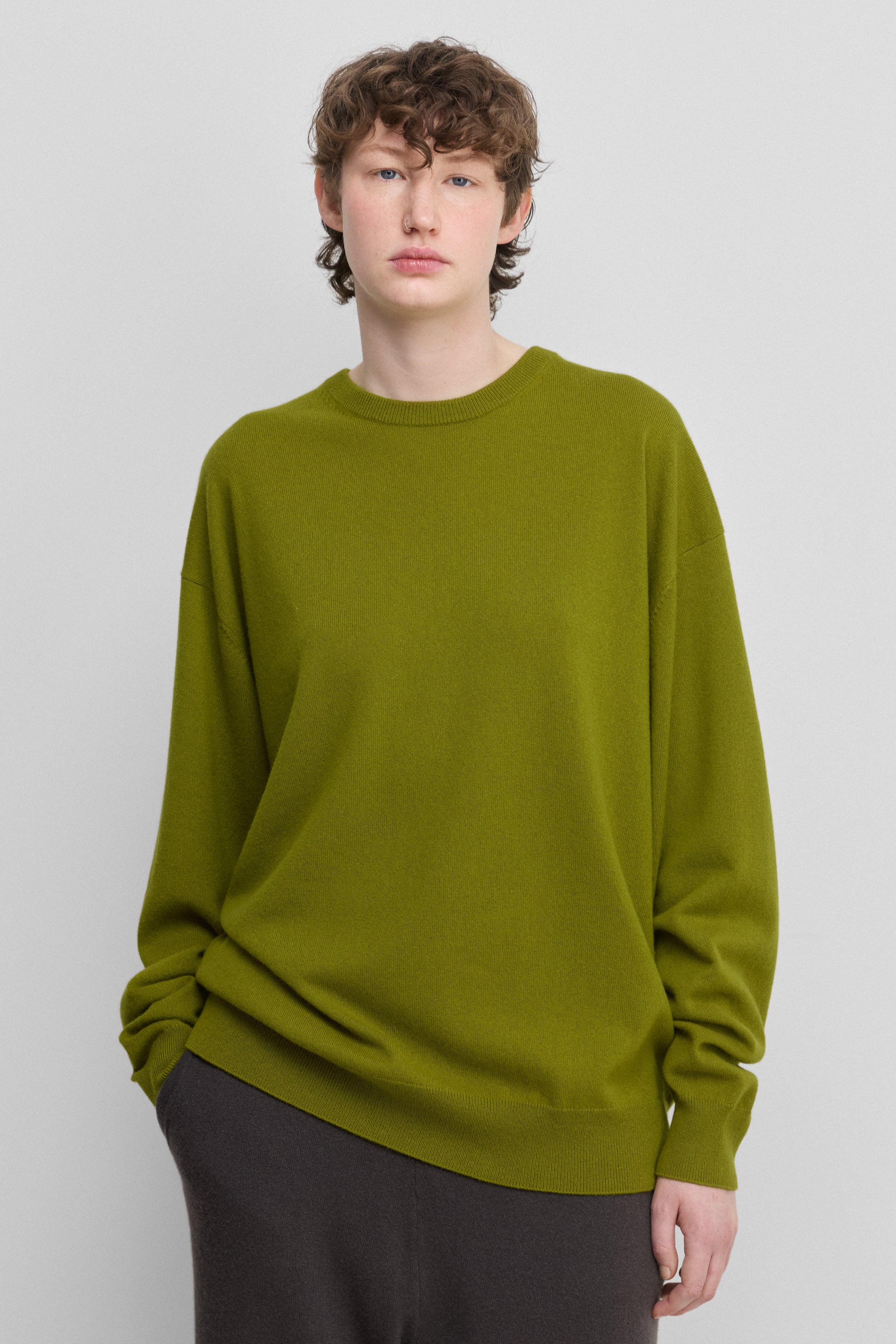 woman wearing a green loose-fit cashmere crew-neck sweater with ribbed hem and cuffs.