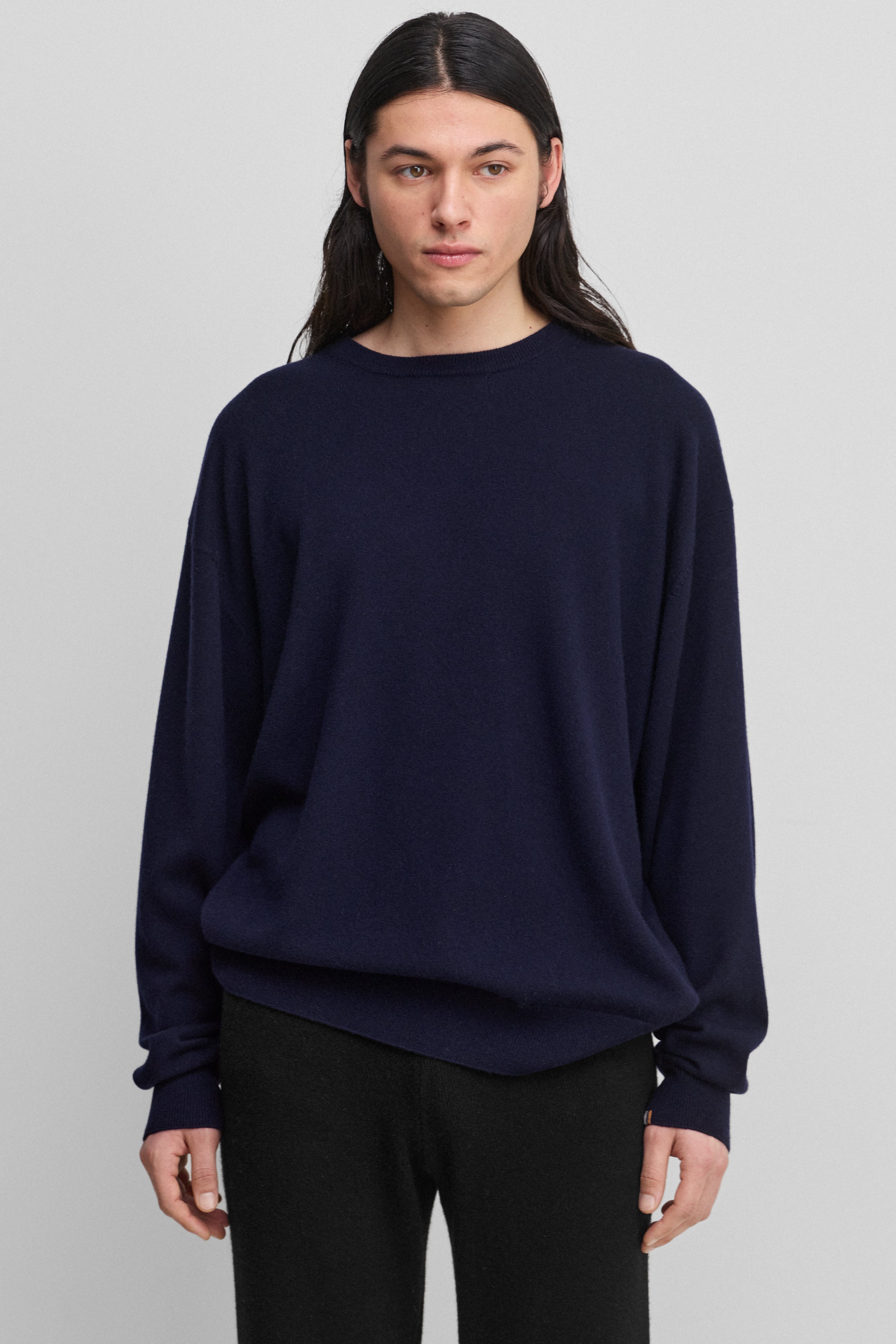 man wearing a navy blue loose-fit cashmere crew-neck sweater with ribbed trims.
