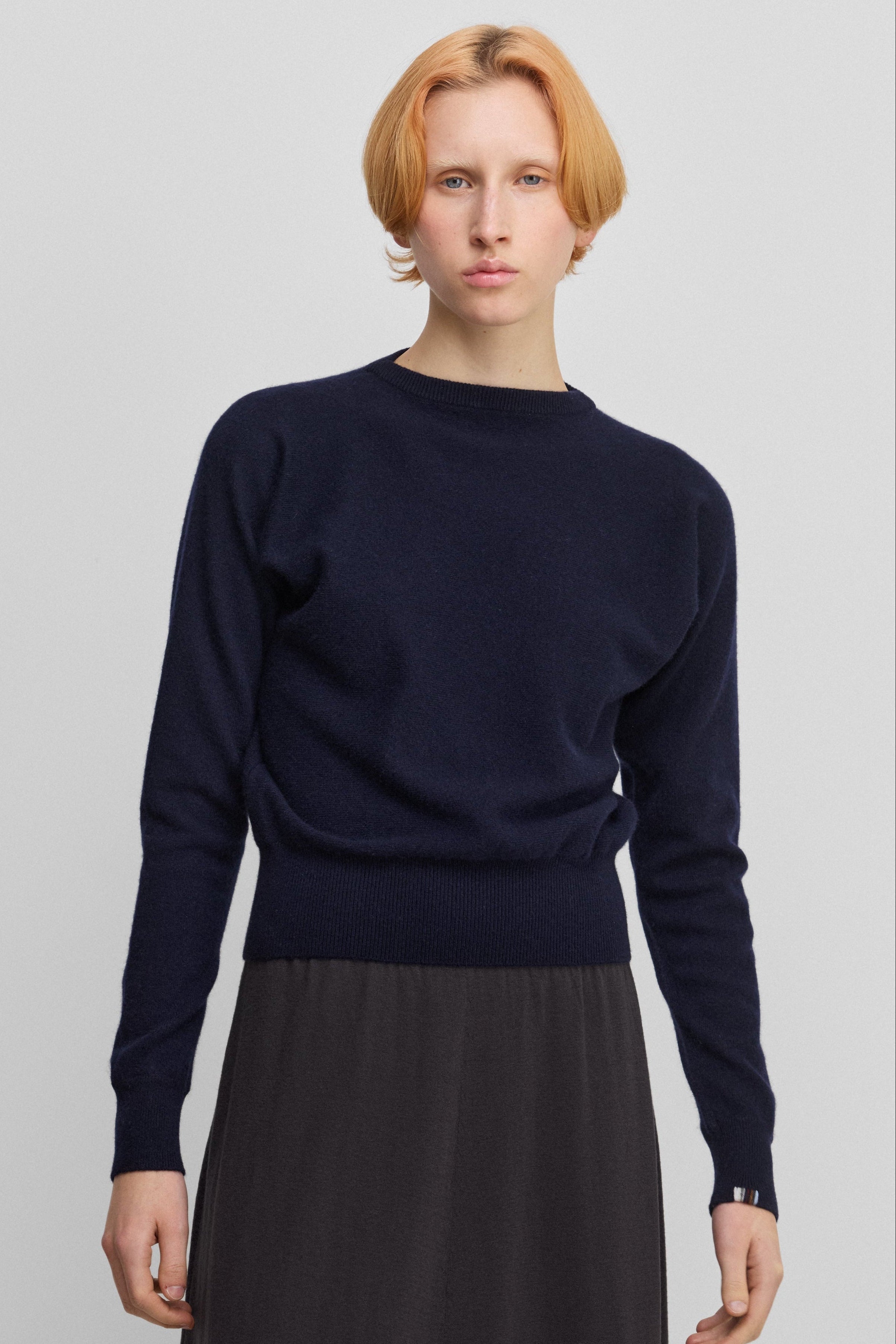 woman wearing a petite navy blue cashmere sweater with bat sleeves.