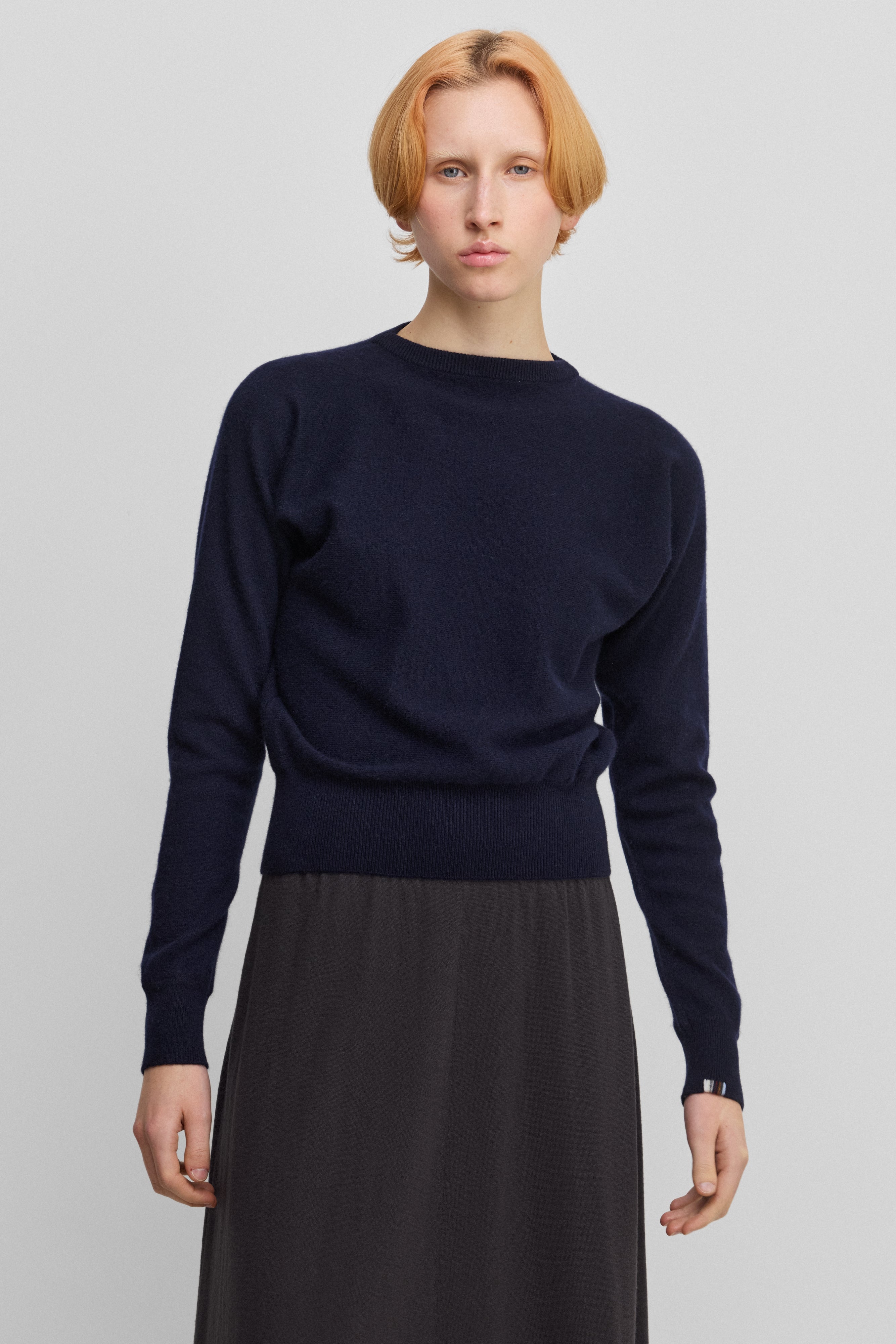 woman wearing a petite navy blue cashmere sweater with bat sleeves.