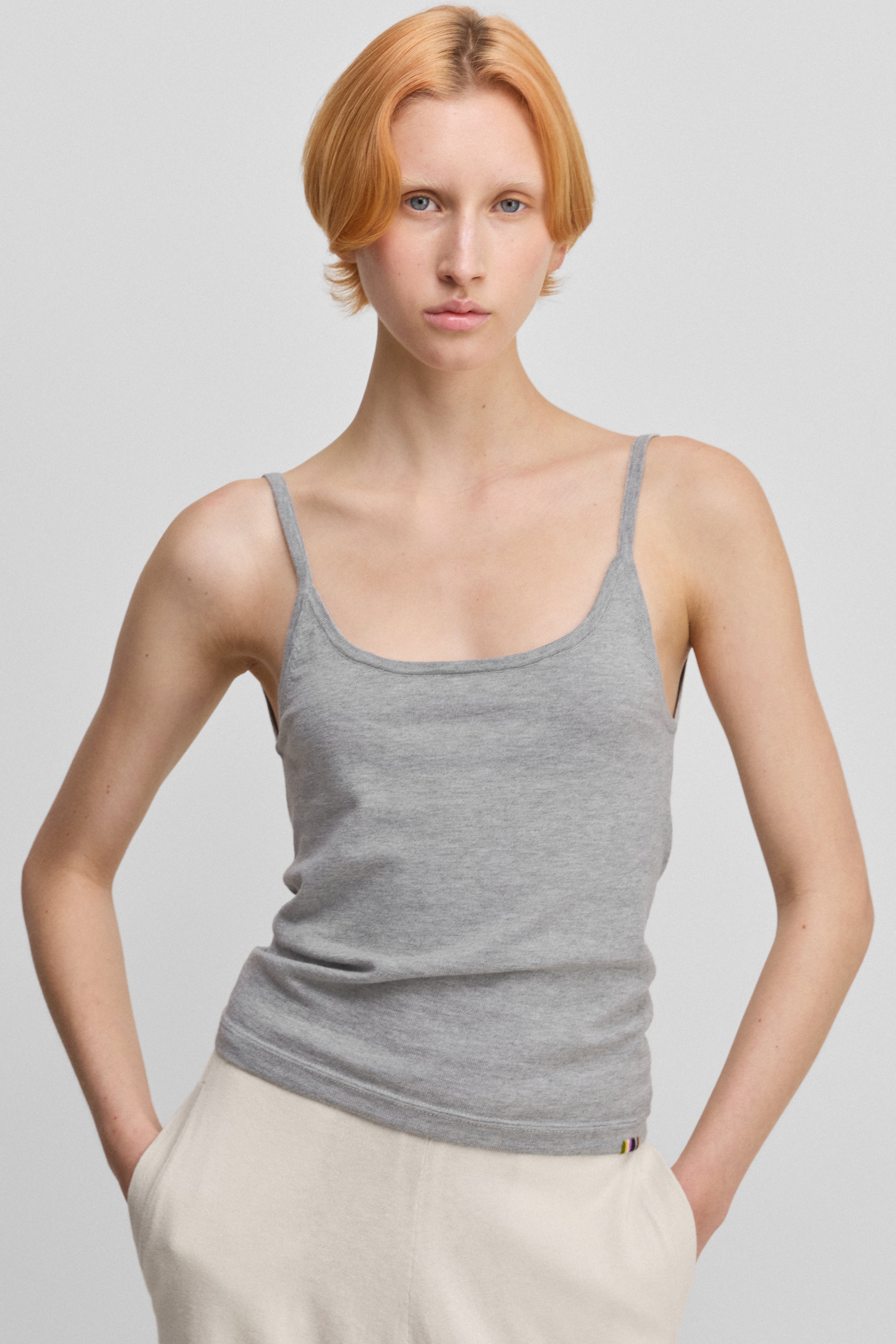 woman wearing a light grey cotton cashmere strap top with a round neckline.