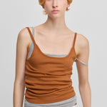 woman wearing an orange cotton cashmere strap top with a round neckline, worn over the same top in grey.