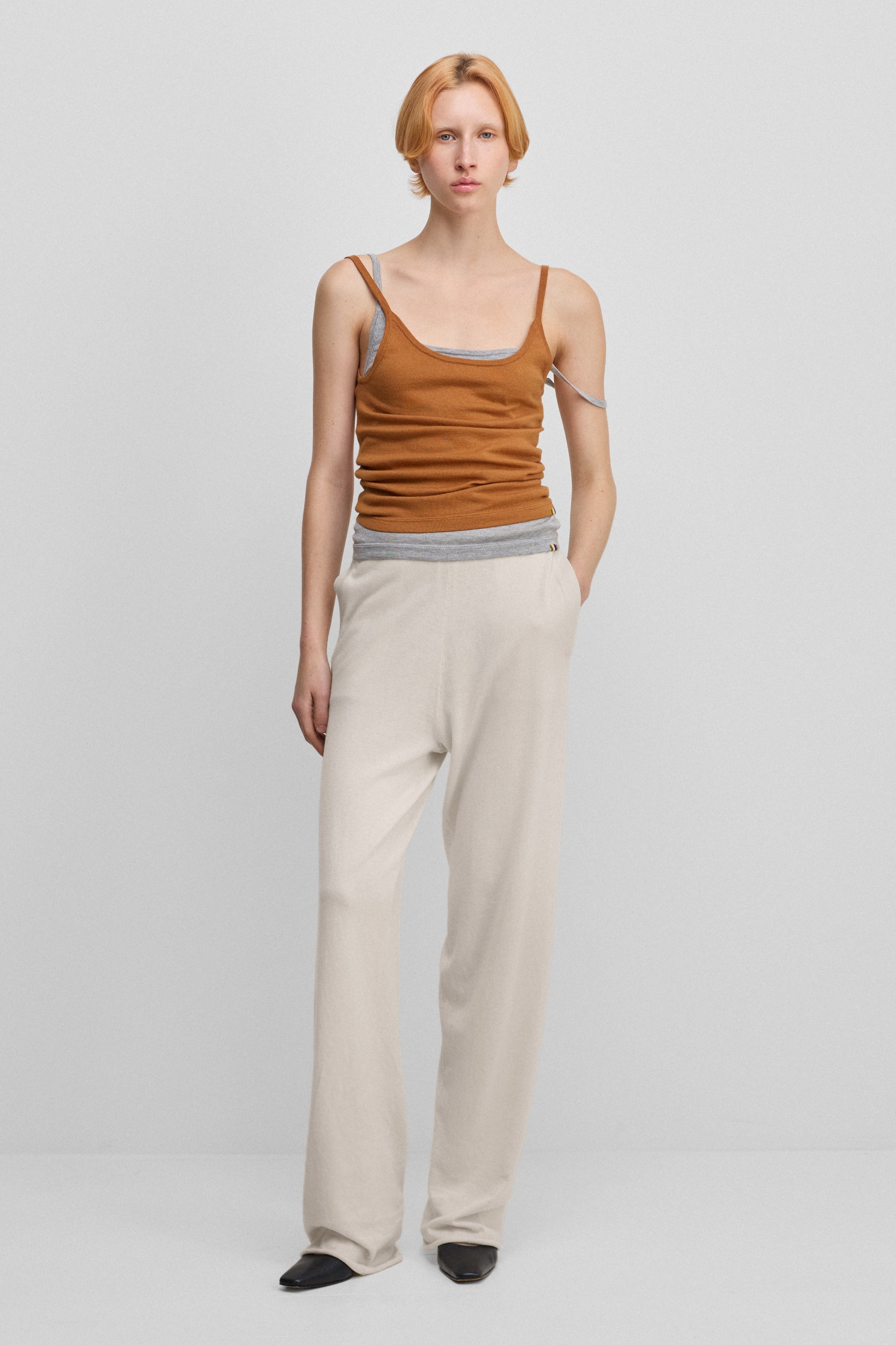 woman wearing loose-fit white cotton cashmere pants with side pockets and drawstring waist.