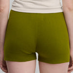 woman wearing fitted green cotton cashmere rib-knit shorts, shown from the back.