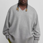 man wearing a grey oversized cashmere v-neck sweater with ribbed hem and cuffs.