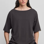 man wearing an oversized dark grey cotton cashmere t-shirt with a boat neck and elbow-length sleeves.
