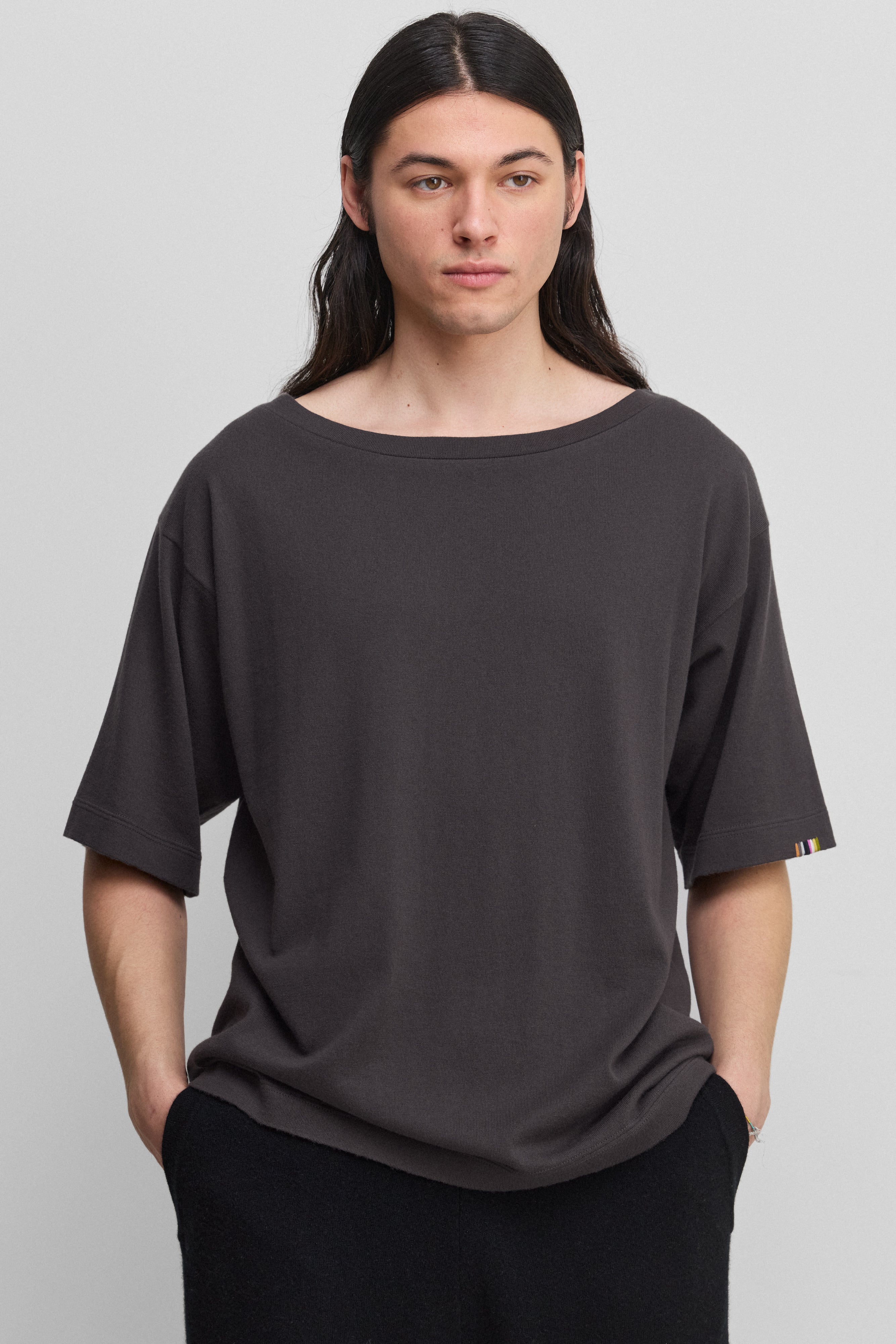 man wearing an oversized dark grey cotton cashmere t-shirt with a boat neck and elbow-length sleeves.