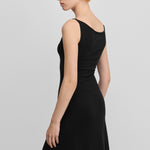 woman wearing a black sleeveless wool cashmere a-line dress, shown from the back.