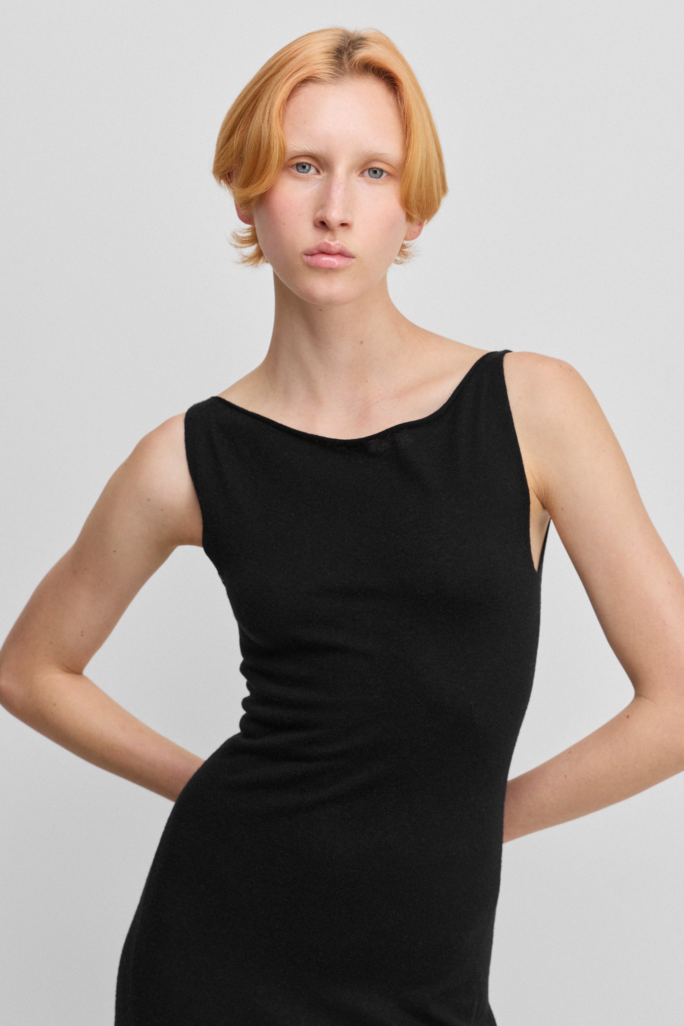 detail of the fitted top and boat neckline of black sleeveless wool cashmere dress.