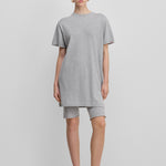 woman wearing a light grey cotton-cashmere mini t-shirt dress, styled with grey biker shorts.