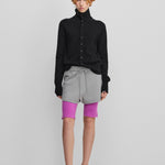 woman wearing a black cashmere button-up cardigan with a rib-knitted collar, styled with grey shorts.