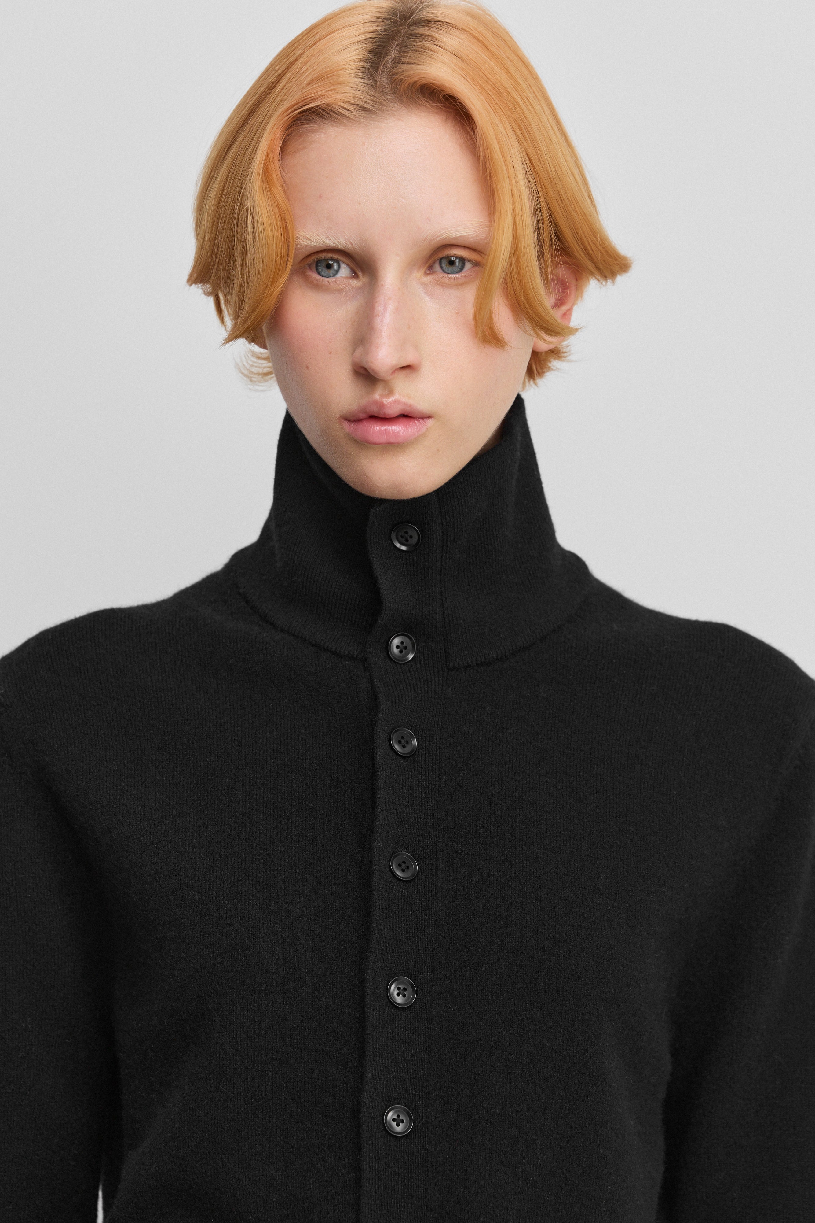 close-up of the rib-knitted collar of a black cashmere button-up cardigan.