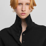 close-up of the rib-knitted collar of a black cashmere button-up cardigan.