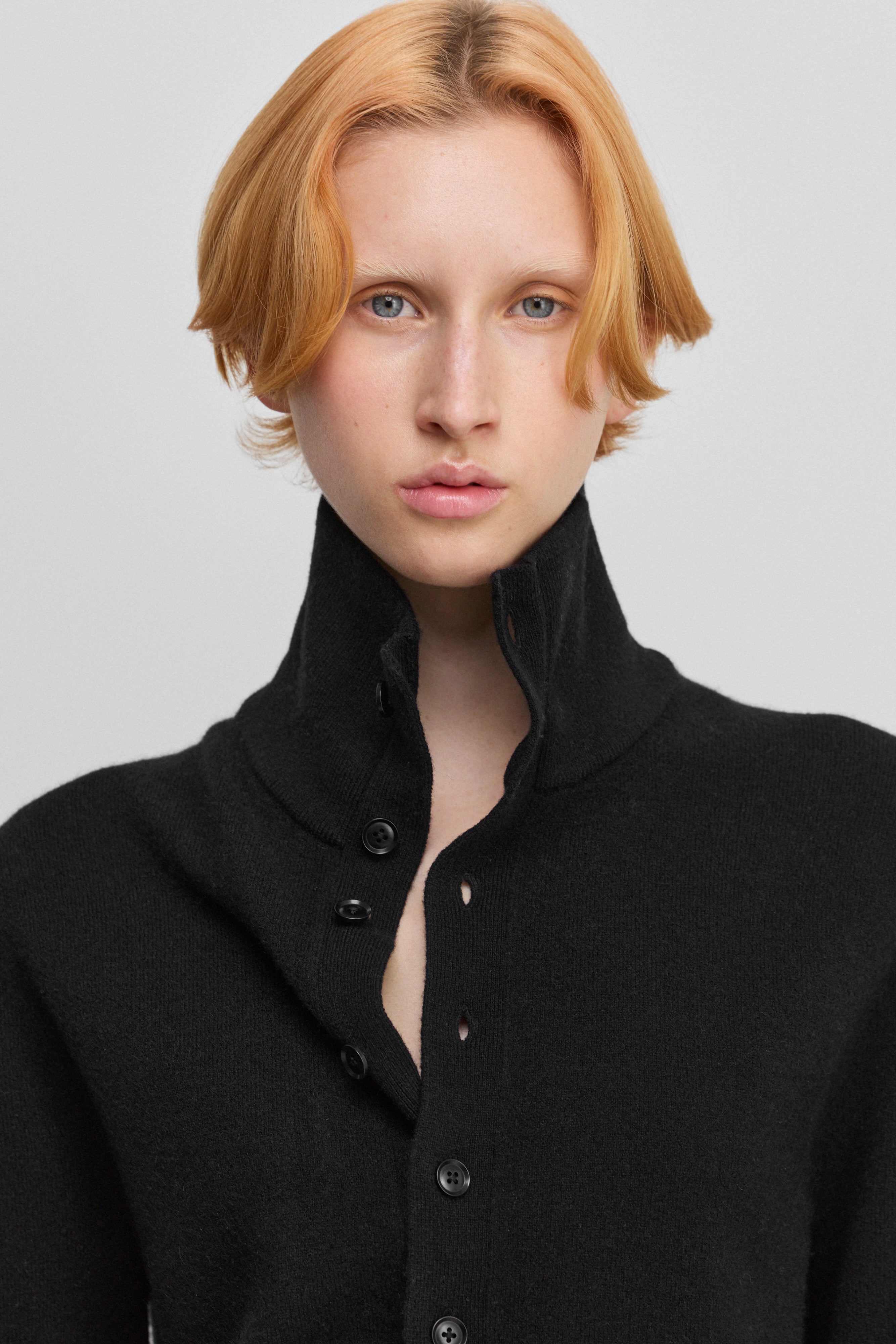 close-up of the rib-knitted collar of a black cashmere button-up cardigan.